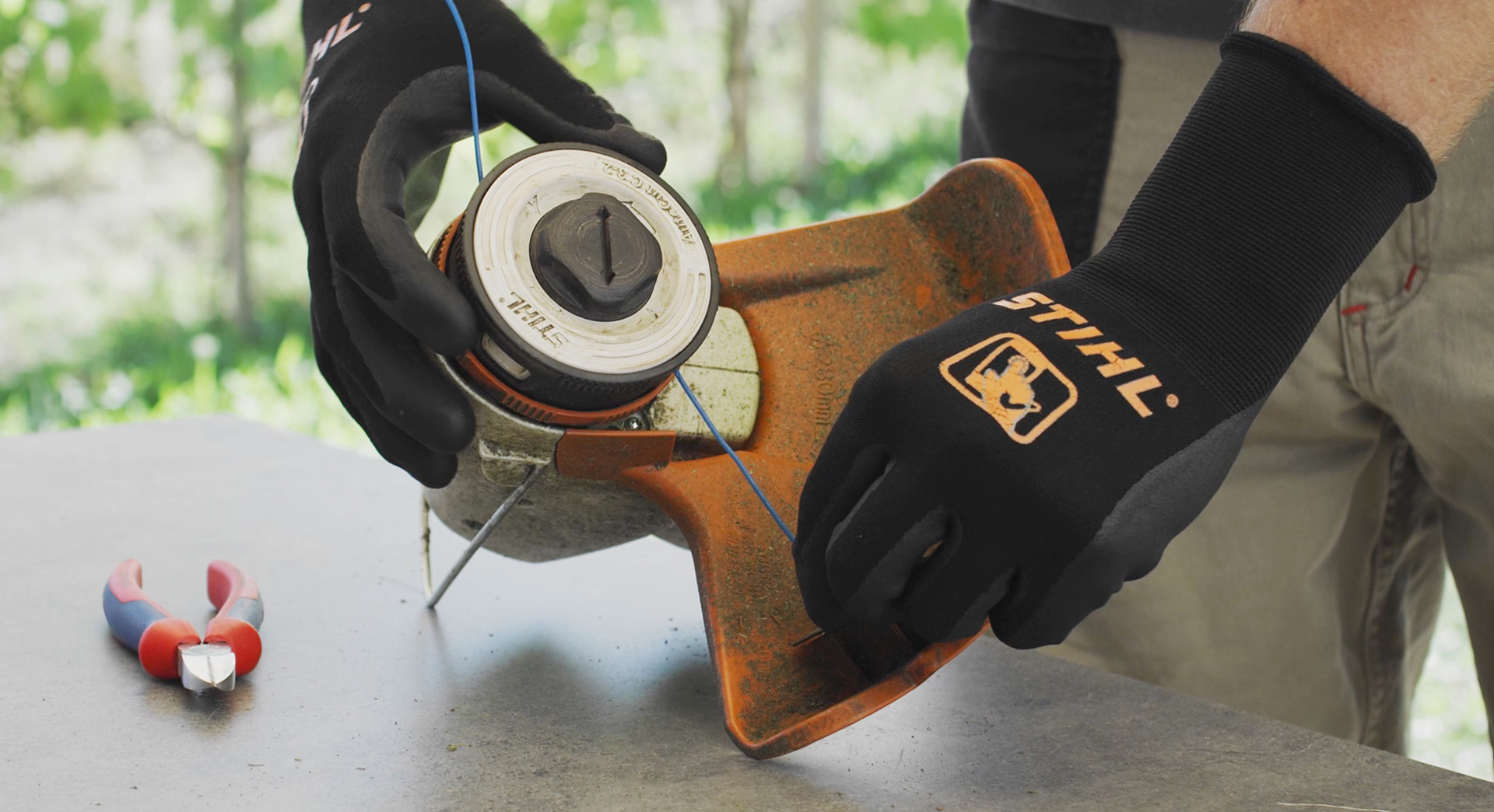 Uma pessoa enrola os fios de corte de uma roçadeira a bateria FSA 57 da STIHL
