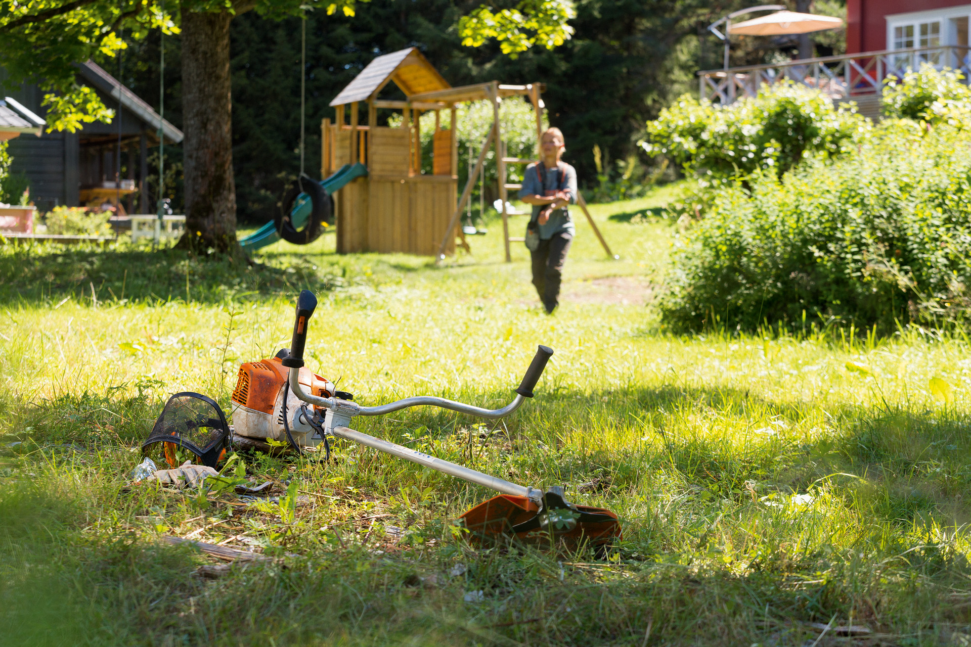 Uma roçadeira STIHL FS 240 na relva e, em segundo plano, um homem prepara-se para a manutenção