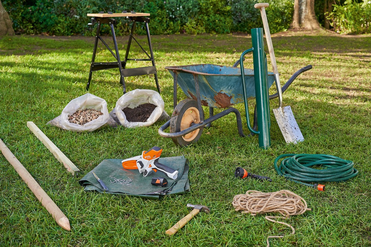 Material de trabalho para plantar árvores, incluindo a podadora a bateria STIHL GTA 26, sobre o gramado