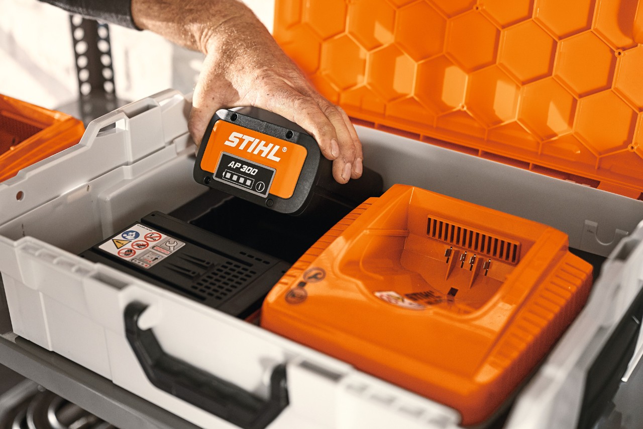 Caixa para bateria STIHL com bateria de íons de lítio AP 300 e máquina a ser carregada
