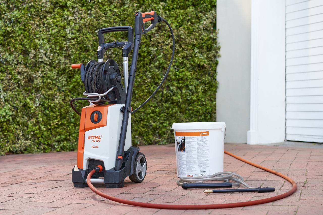 Lavadora de alta pressão STIHL RE 130 PLUS e areia calibrada SB 90 para injeção de areia úmida à frente de uma garagem 