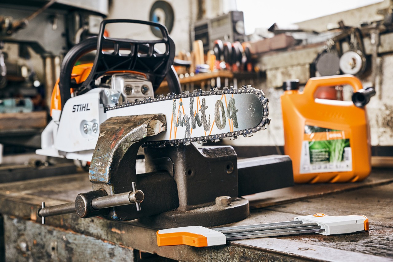 Motosserra a gasolina STIHL MS 261 C-M com barra-guia Light 04 junto de uma mistura de combustível STIHL MotoMix antes de ser afiada