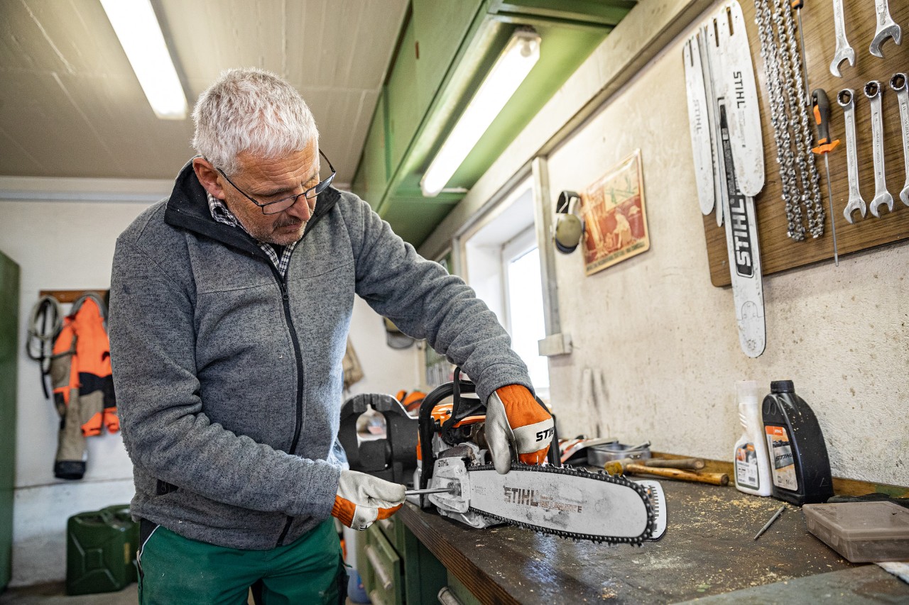 Um homem mostra como esticar a corrente da motosserra numa máquina da STIHL numa oficina