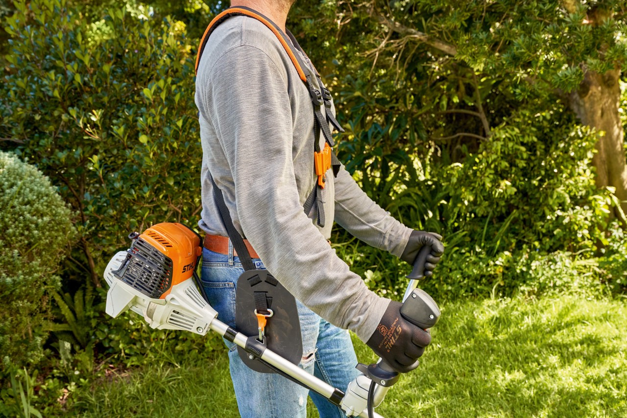 Homem a levantar a motorroçadora a gasolina STIHL FS&nbsp;91 do chão para começar a cortar a relva 