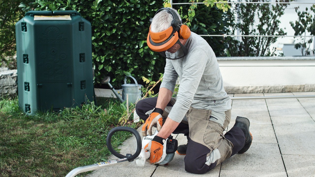 Alguém com vestuário de proteção empurra a motorroçadora a gasolina STIHL FS&nbsp;38 contra o chão