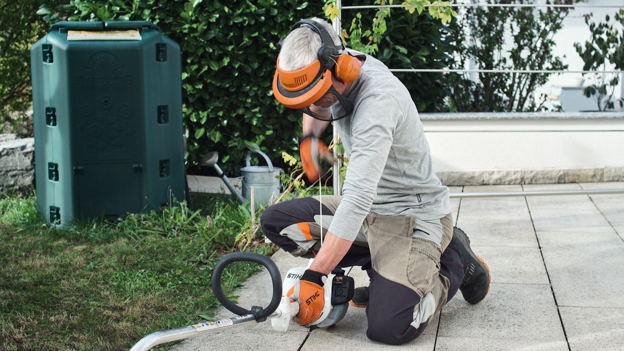 Alguém com vestuário de proteção puxa a corda de arranque da motorroçadora a gasolina STIHL FS&nbsp;38