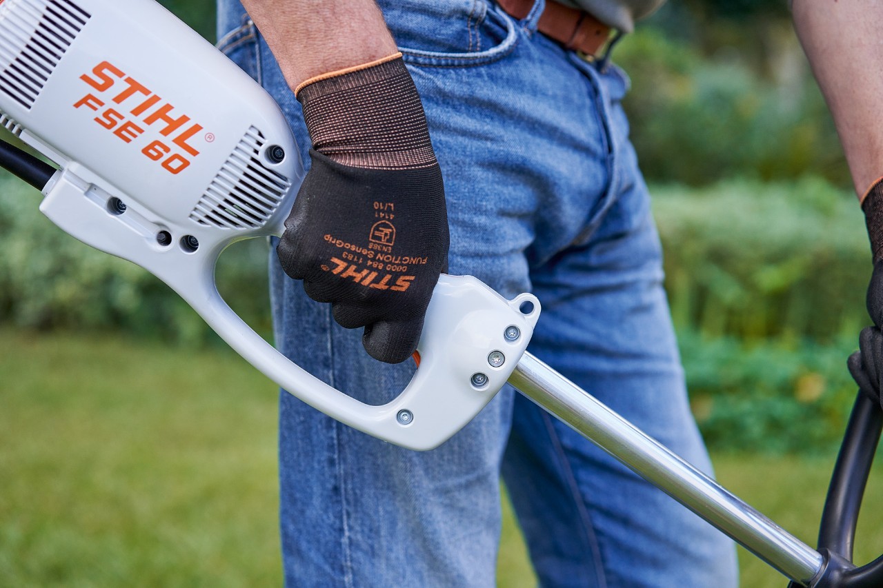 Um homem prime o interruptor na pega de comando da motorroçadora elétrica STIHL FSE&nbsp;60