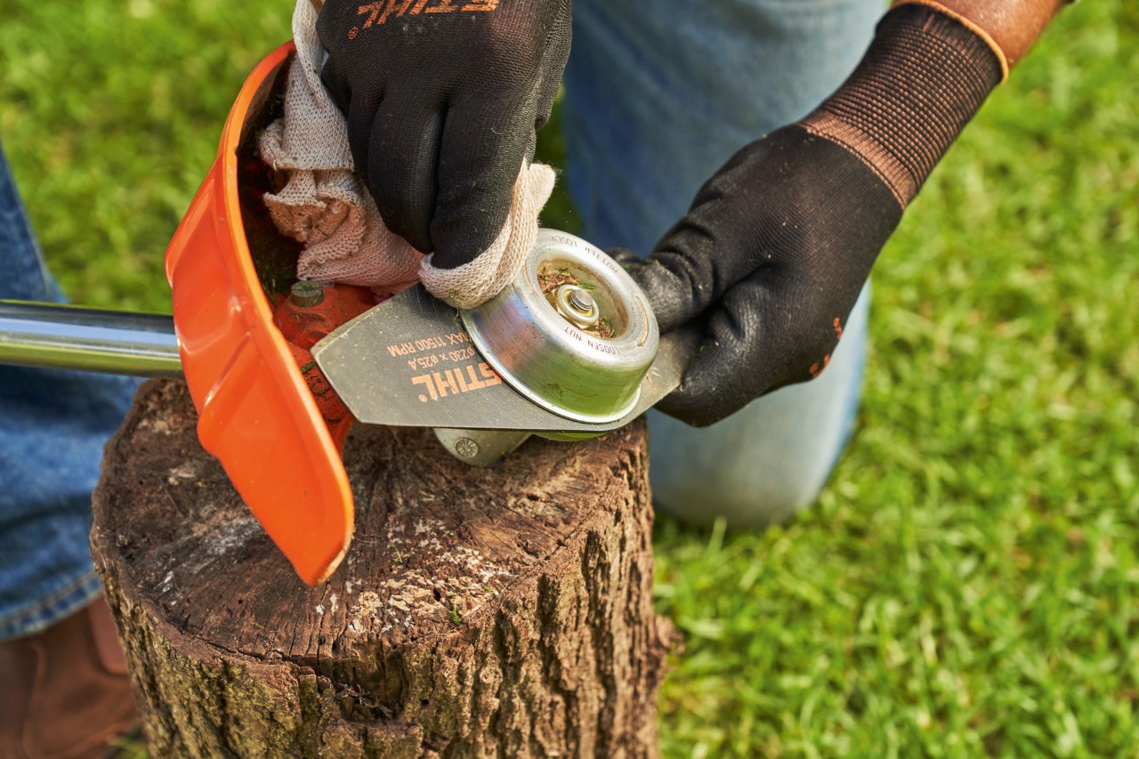 A lâmina metálica de uma roçadeira STIHL é limpa com um pano húmido