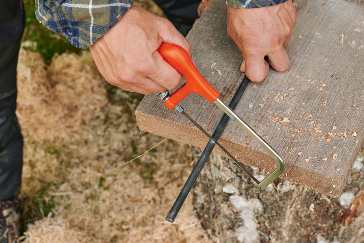 Fazer uma estrela de madeira numa vareta: uma vareta de metal a ser cortada com uma serra para metais.
