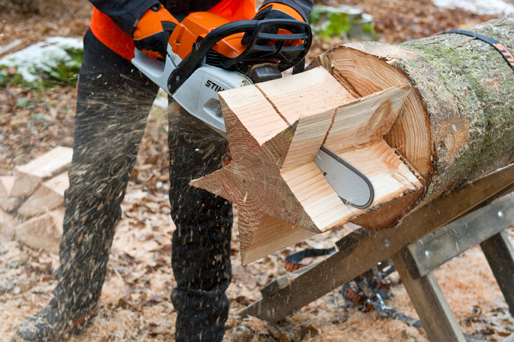 Fazer uma estrela de madeira: uma pessoa a cortar uma estrela a partir de um tronco, utilizando a motosserra STIHL MS 261 C-M