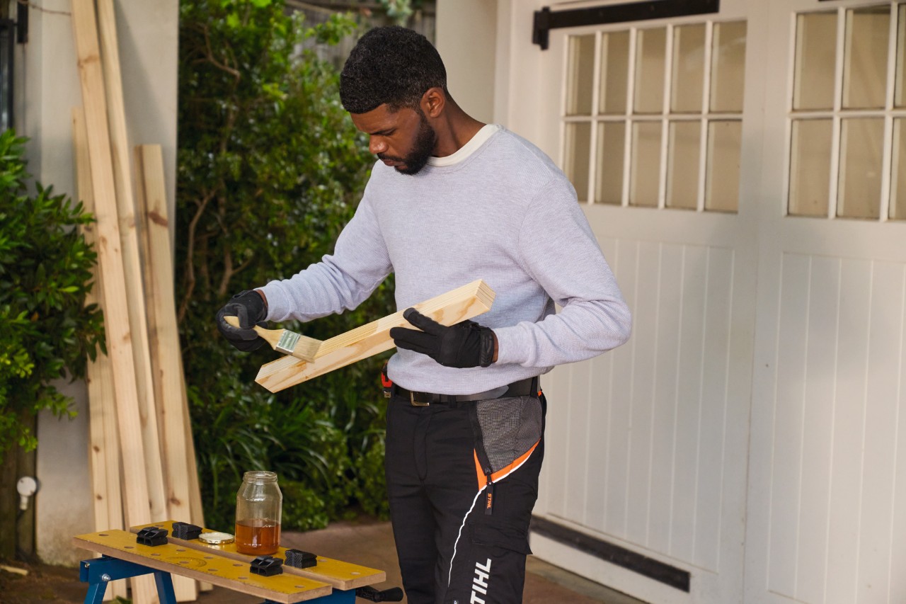 Um homem a pintar um pedaço de madeira com óleo