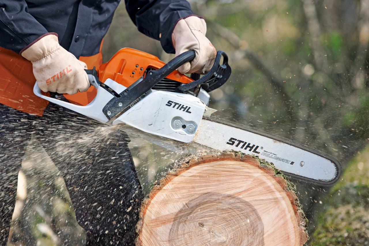 Homem cortando um tronco de árvore com uma motosserra STIHL