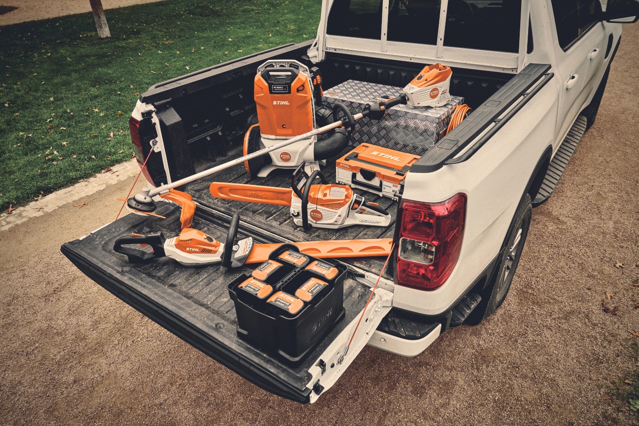 Várias ferramentas movidas a bateria do sistema STIHL AP e as baterias correspondentes na área de carga de um veículo