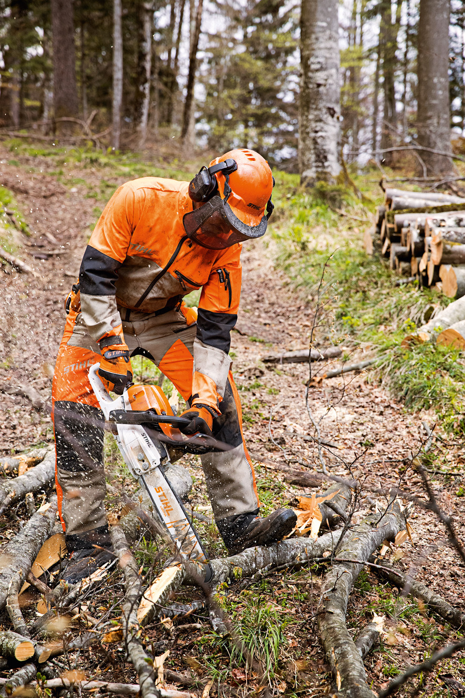 Homem usa uma combinação de equipamentos de proteção auditiva no trabalho profissional numa floresta