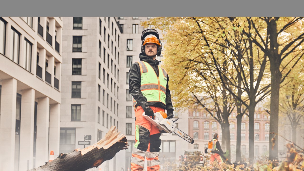 Um homem com uma motosserra STIHL à frente de uma árvore