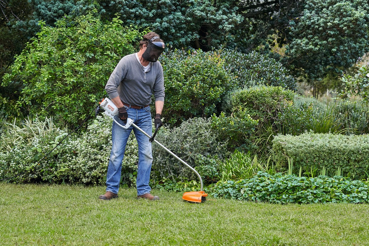 Uma mulher corta o buxo com a minipodadora a bateria STIHL HSA 26 recorrendo a um molde de cartão em forma de bola